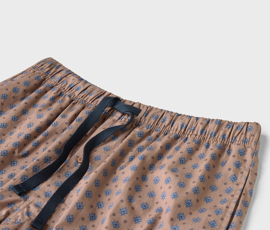 Nahaufnahme einer beige Hose mit blauem Blumenmuster und marineblauem Kordelzug.