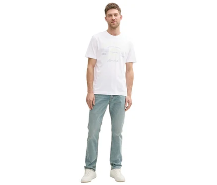 Mann steht in Jeans und weißem Tom Tailor T-Shirt mit Logo.