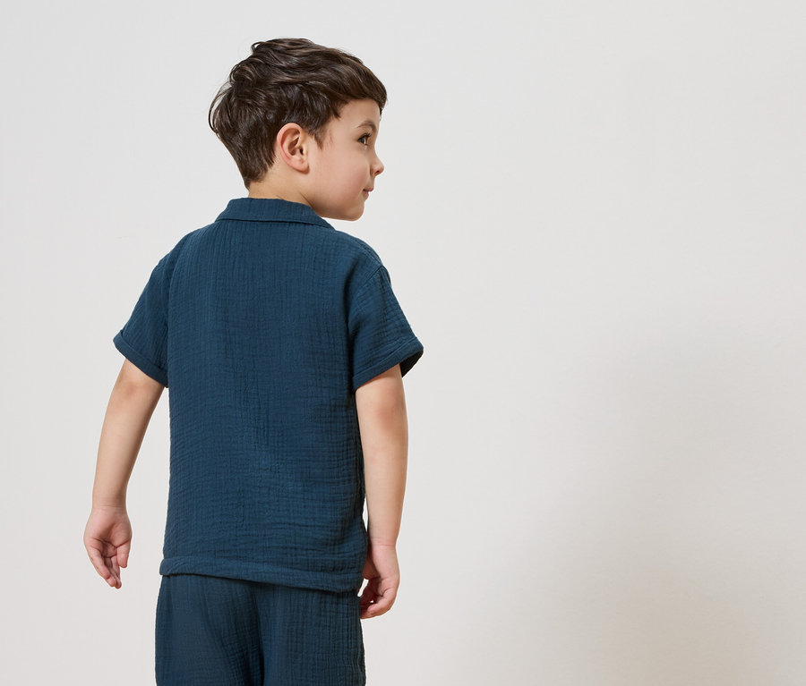 Ein Junge trägt einen dunkelblauen Pyjama.