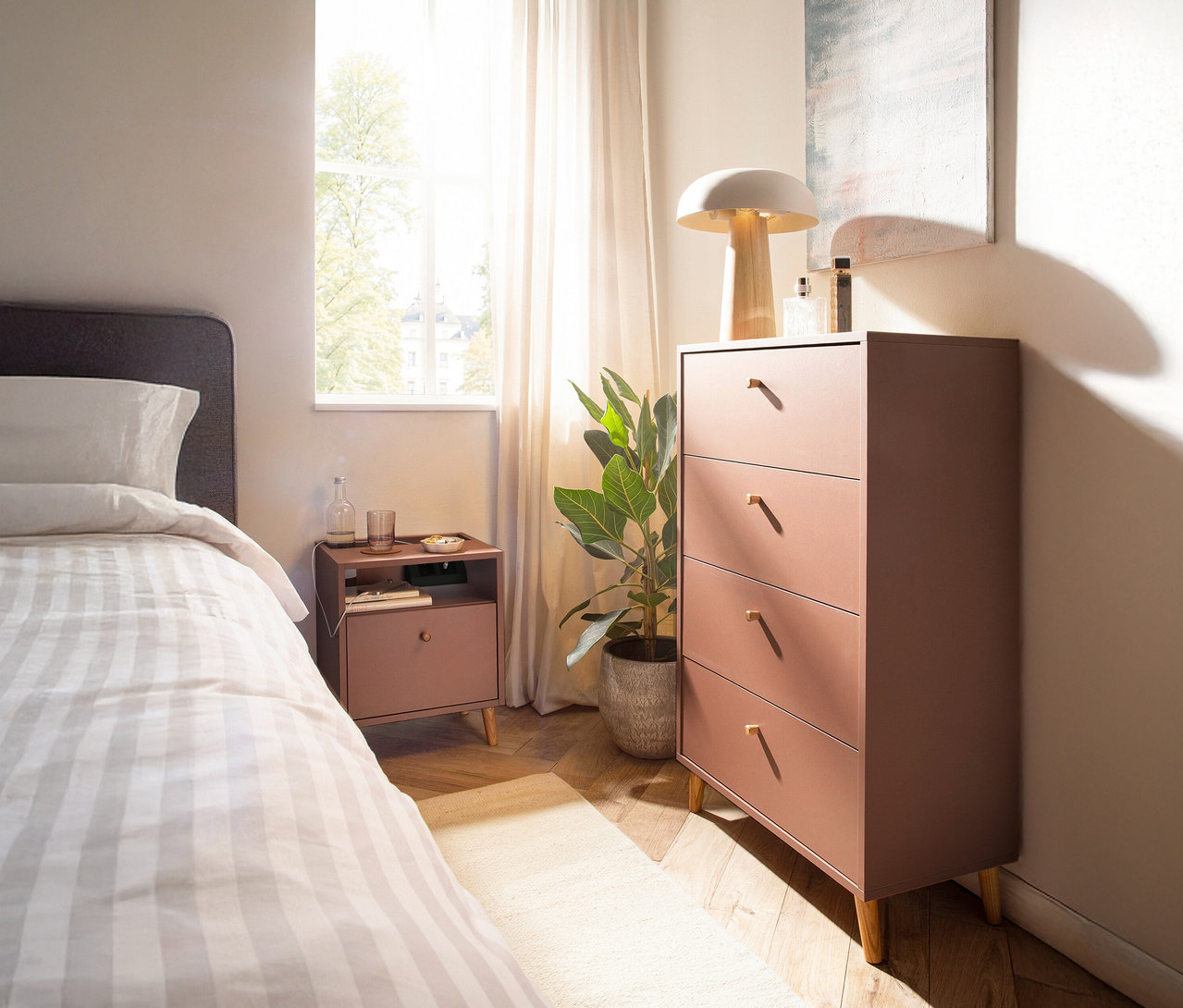 Schlafzimmer mit mauvefarbenem Nachttisch »Bjarne« mit Ladefunktion neben einem Bett und einer Kommode.