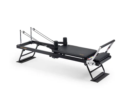 Schwarzer Pilates-Reformer mit gepolstertem Wagen, verstellbarer Fußstange, Schulterstützen und Seilen mit Rollen, darunter bunte Widerstandsfedern.