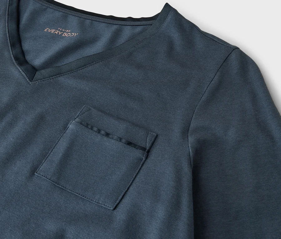 Nahaufnahme eines dunkelblaugrauen V-Ausschnitt-T-Shirts mit Brusttasche. Der Schriftzug 'TCHIBO EVERY BODY' ist innen am Kragen sichtbar.