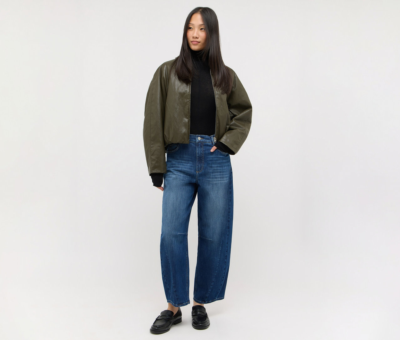 Frau in schwarzem Rollkragenpullover, dunkelgrüner Bomberjacke und Angels Denim »Elly« Jeans, dazu schwarze Loafer.