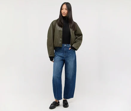 Frau in schwarzem Rollkragenpullover, dunkelgrüner Bomberjacke und Angels Denim »Elly« Jeans, dazu schwarze Loafer.