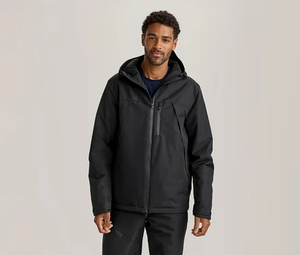 Mann trägt eine schwarze Kapuzenjacke über einem dunkelblauen T-Shirt und schwarze Hosen.