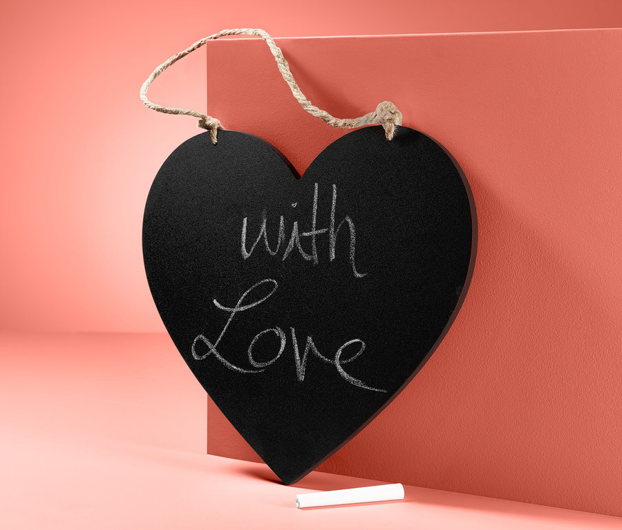 Eine Kreidetafel in Herzform mit der Aufschrift "With Love" und Kreide unten.
