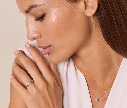 Frau mit hellbraunen Haaren blickt auf 585 Gold-Ring mit Brillant am Ringfinger ihrer linken Hand.