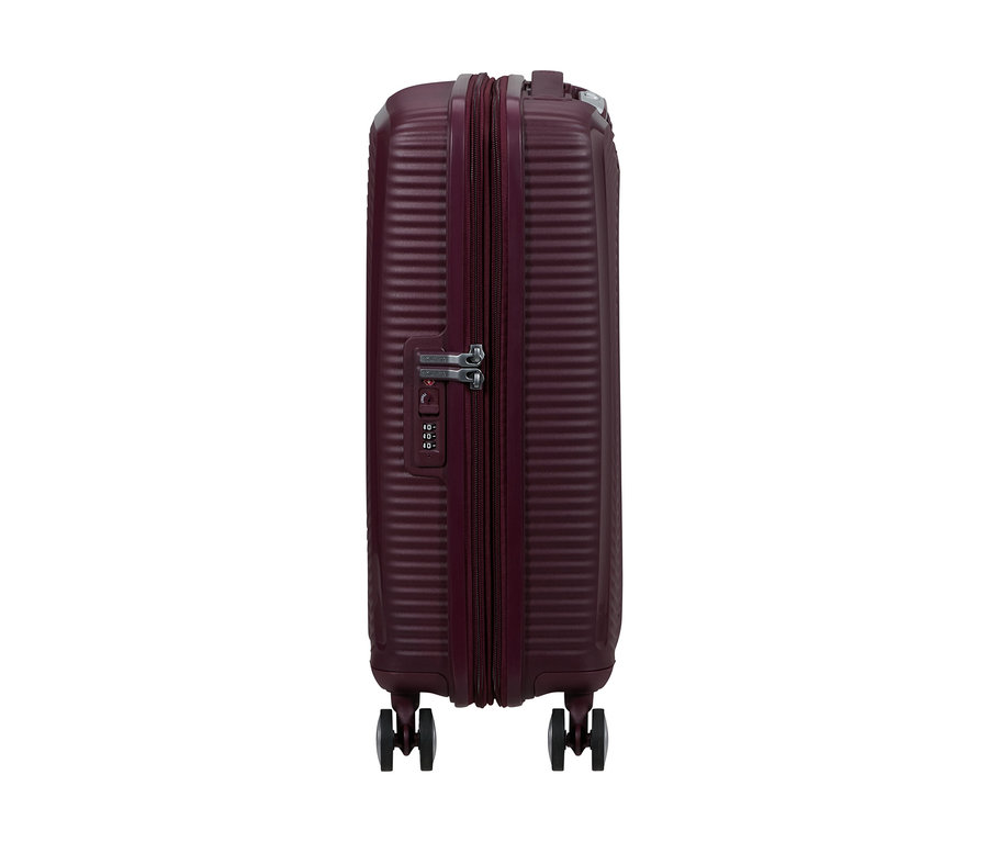 American Tourister Hartschalen-Koffer Soundbox Spinner in Wildkirsche, klein, mit geriffelter Oberfläche, Reißverschluss und Zahlenschloss, von der Seite stehend.
