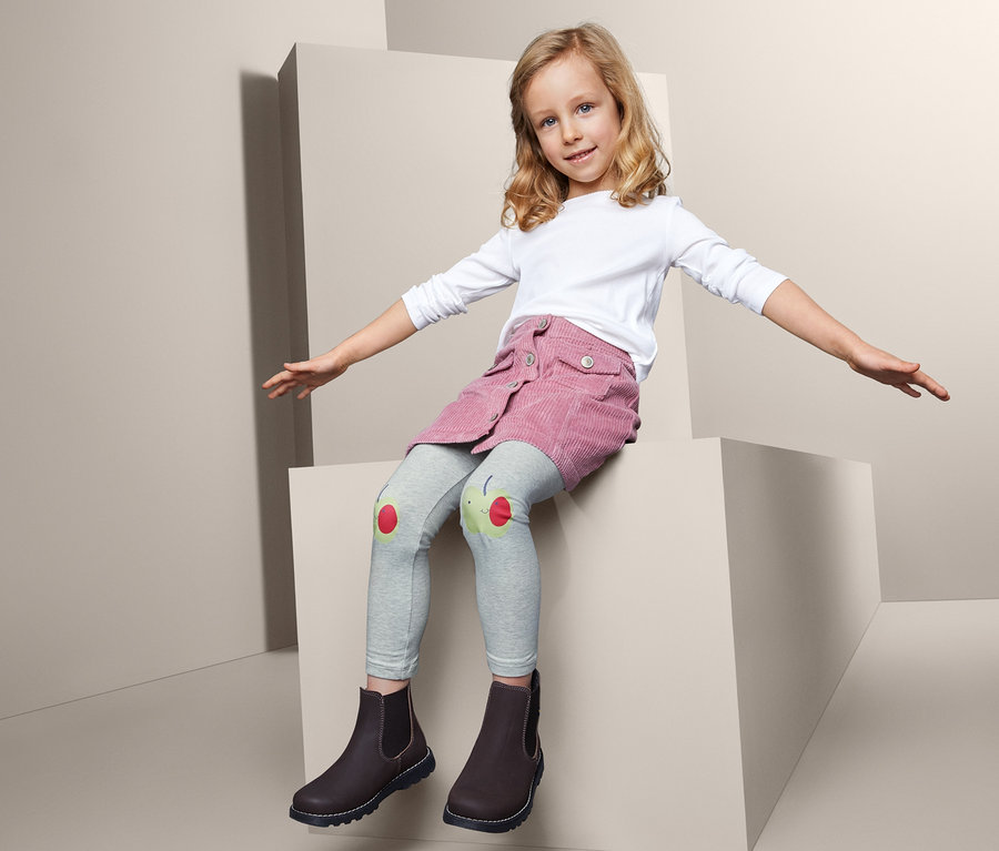 Mädchen sitzt auf einem Block und trägt 2 Leggings.