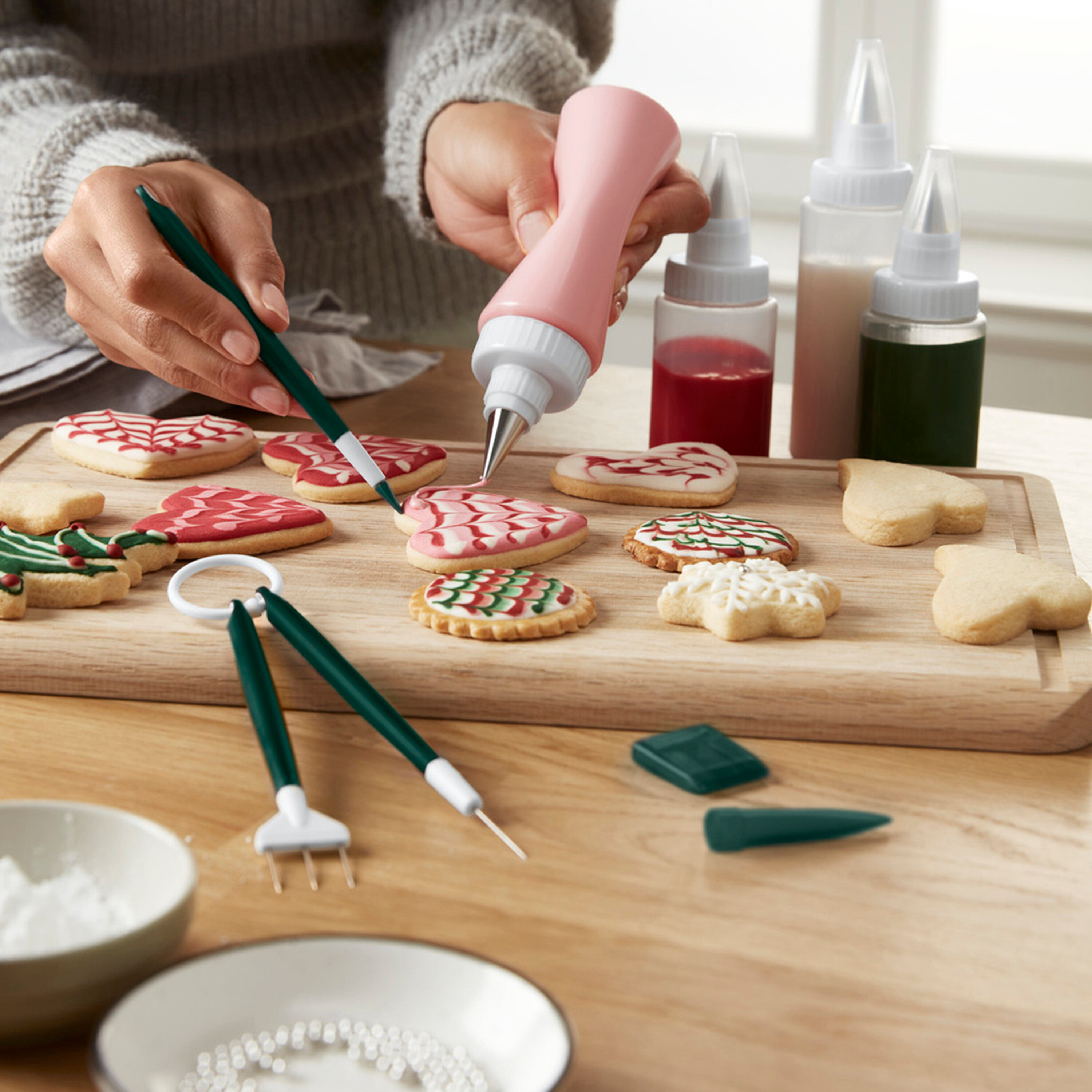 Frau verziert Lebkuchen mit Zuckerguss mit einer Spritztüte und einem Pinsel.