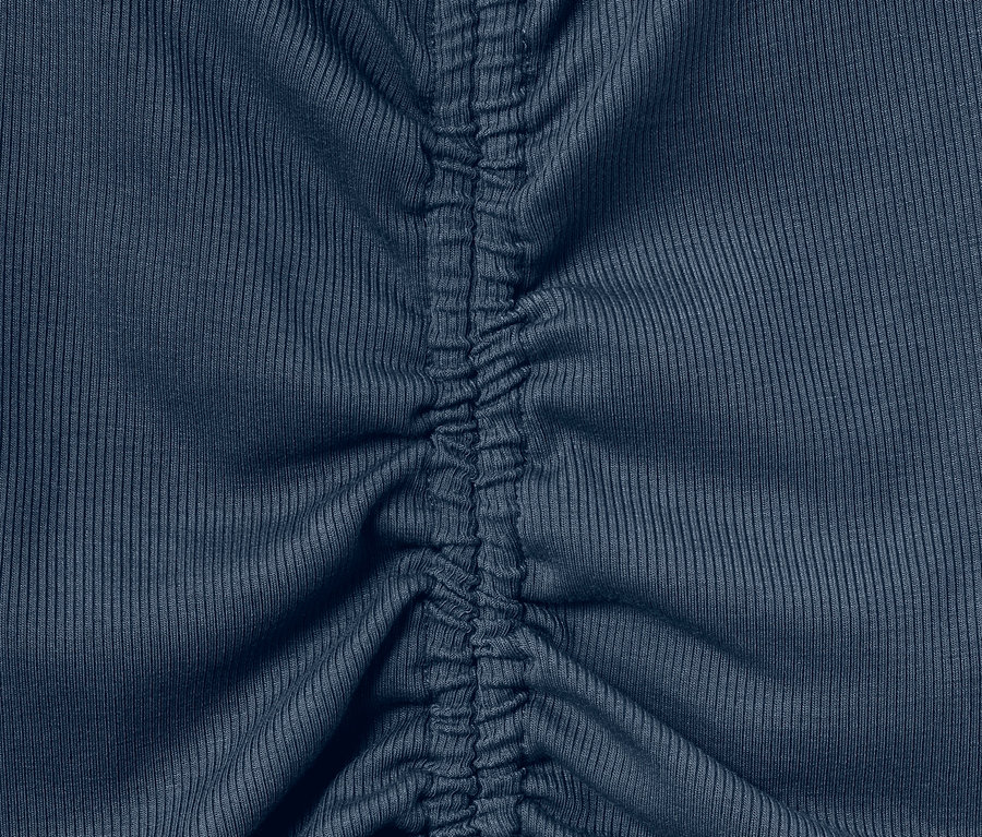 Detailansicht eines blauen Sportshirts mit Raffung in der Mitte.
