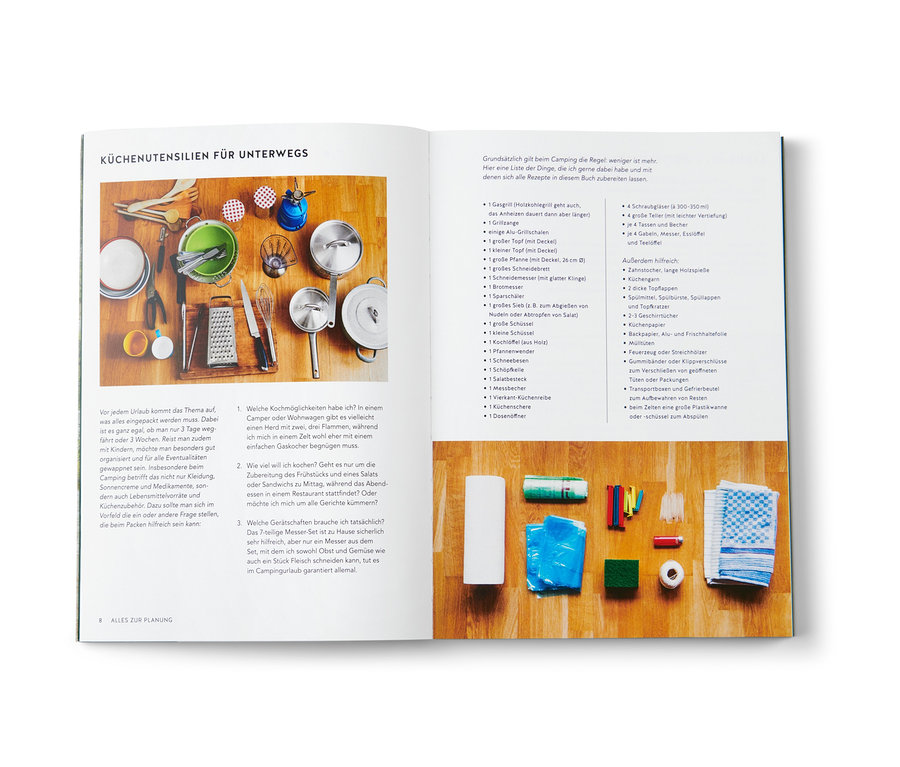 Camping-Küchenutensilien sind auf einem Tisch ausgebreitet, zusammen mit dem Buch "Campingküche".