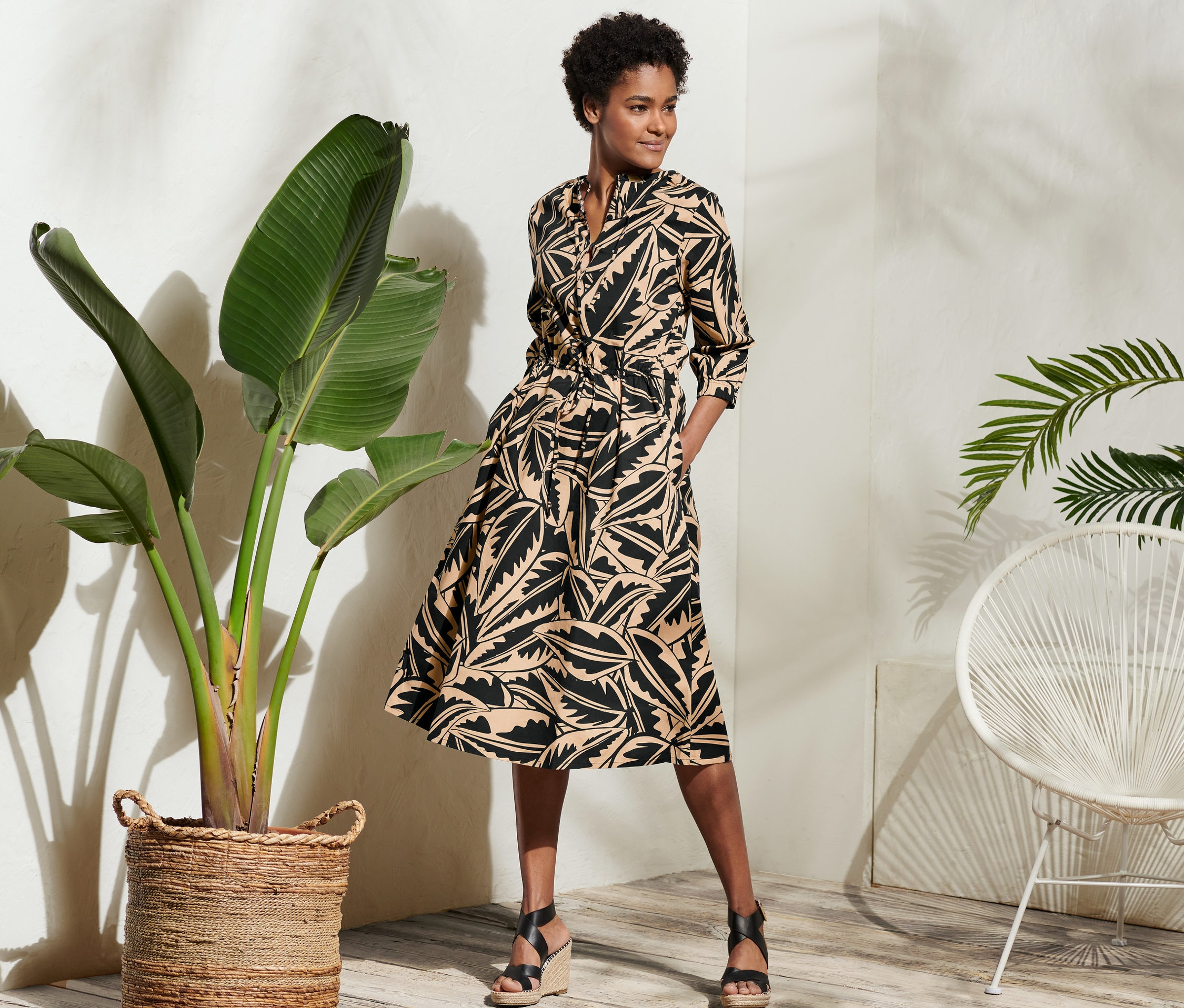 Frau posiert in Popeline-Kleid mit Palmenblätter-Druck.