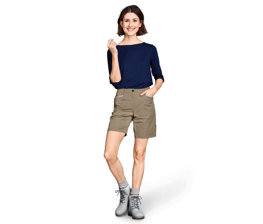 Frau posiert in Softshell-Funktionsshorts und blauem Oberteil.