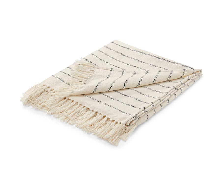 Gefaltete beige Wohndecke mit Fransen und dünnen schwarzen Streifen.