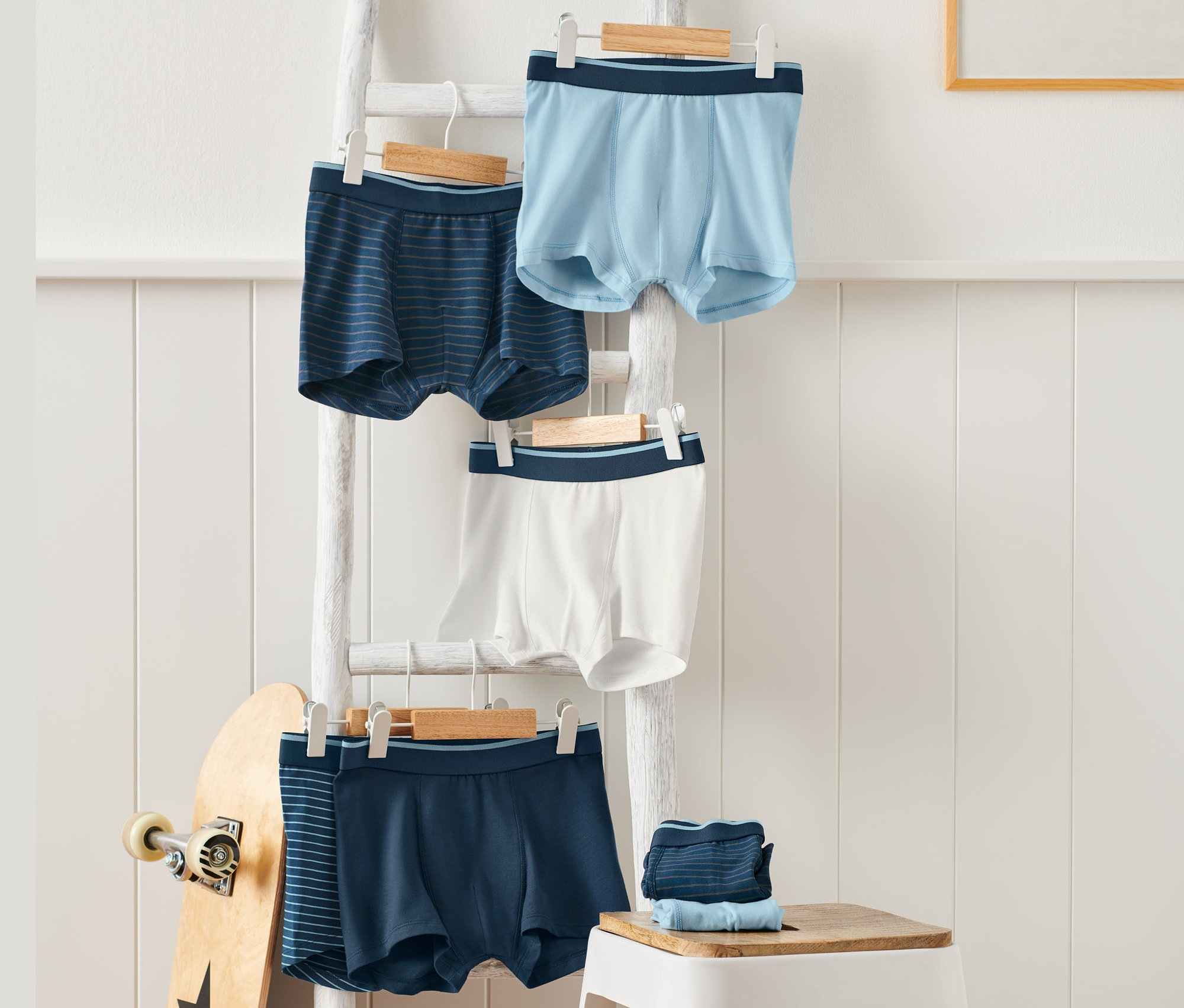 Blaue 7er-Pack Slipboxer hängen an Kleiderbügeln auf einer weissen Leiter.