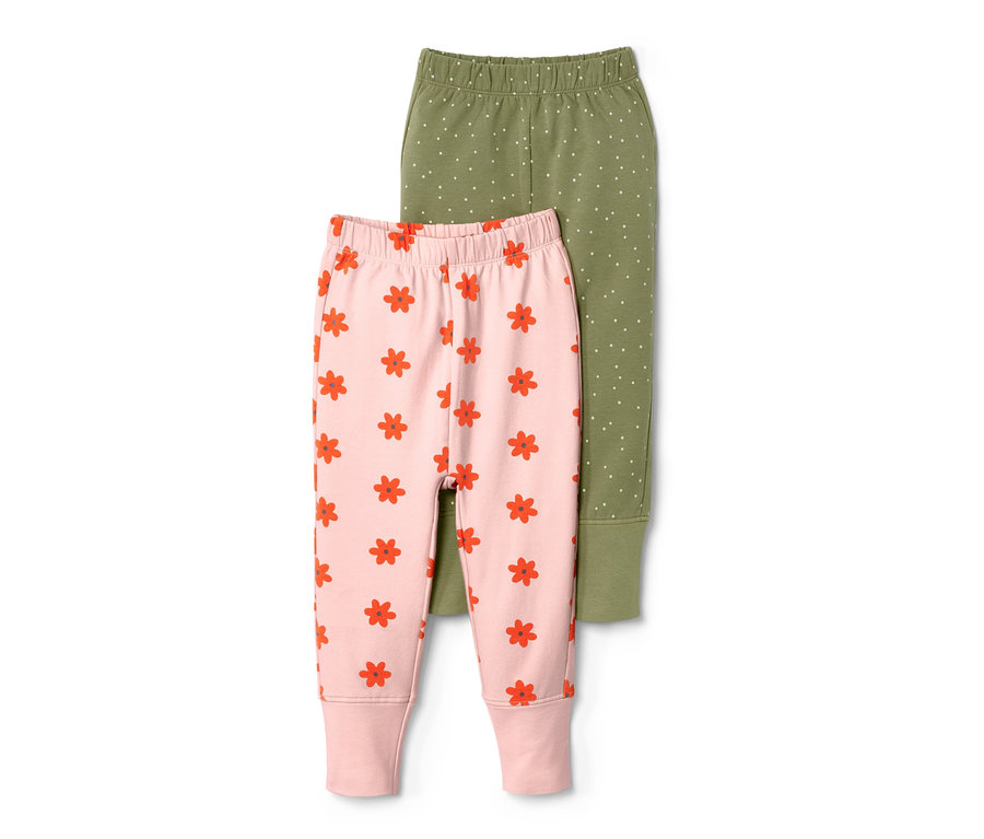 Zwei Baby-Sweathosen, eine rosa mit roten Blumen und eine olivgrün mit weißen Punkten.