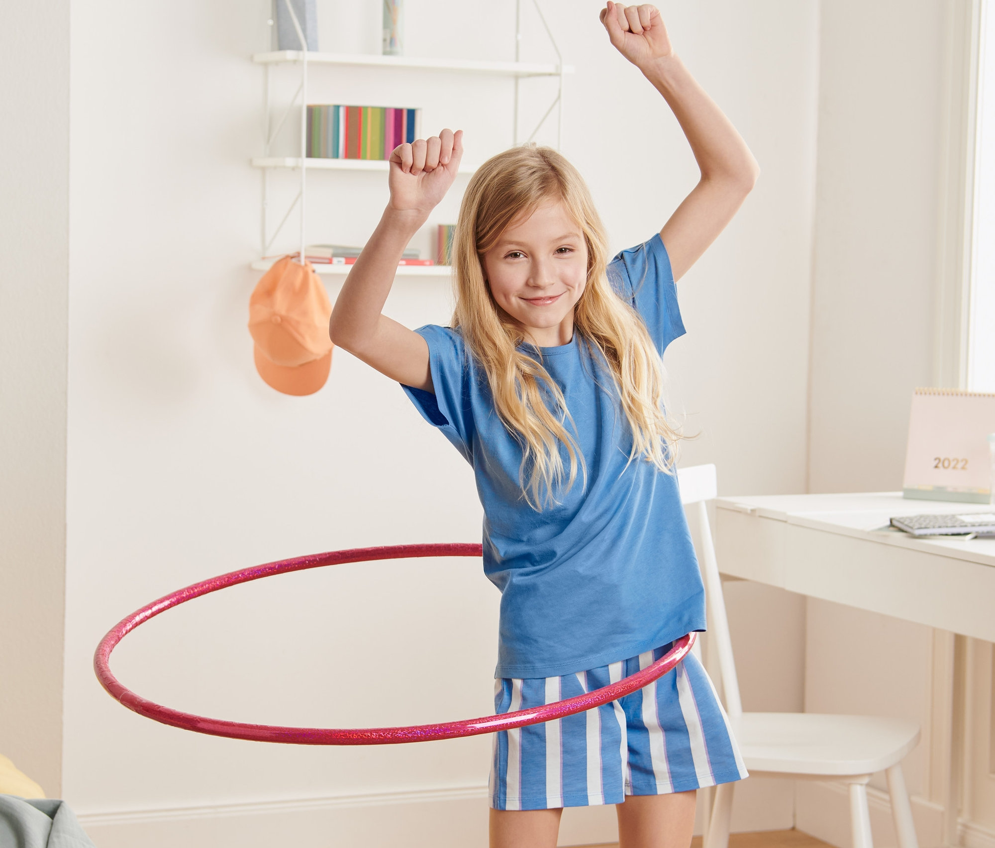 Mädchen turnt mit Hula-Hoop-Reifen im Shorty-Pyjama.