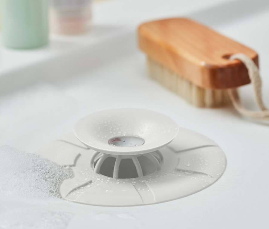 Nahaufnahme eines weißen 2-in-1: Abflusssieb und -verschlusses in einem Waschbecken mit Schaum.