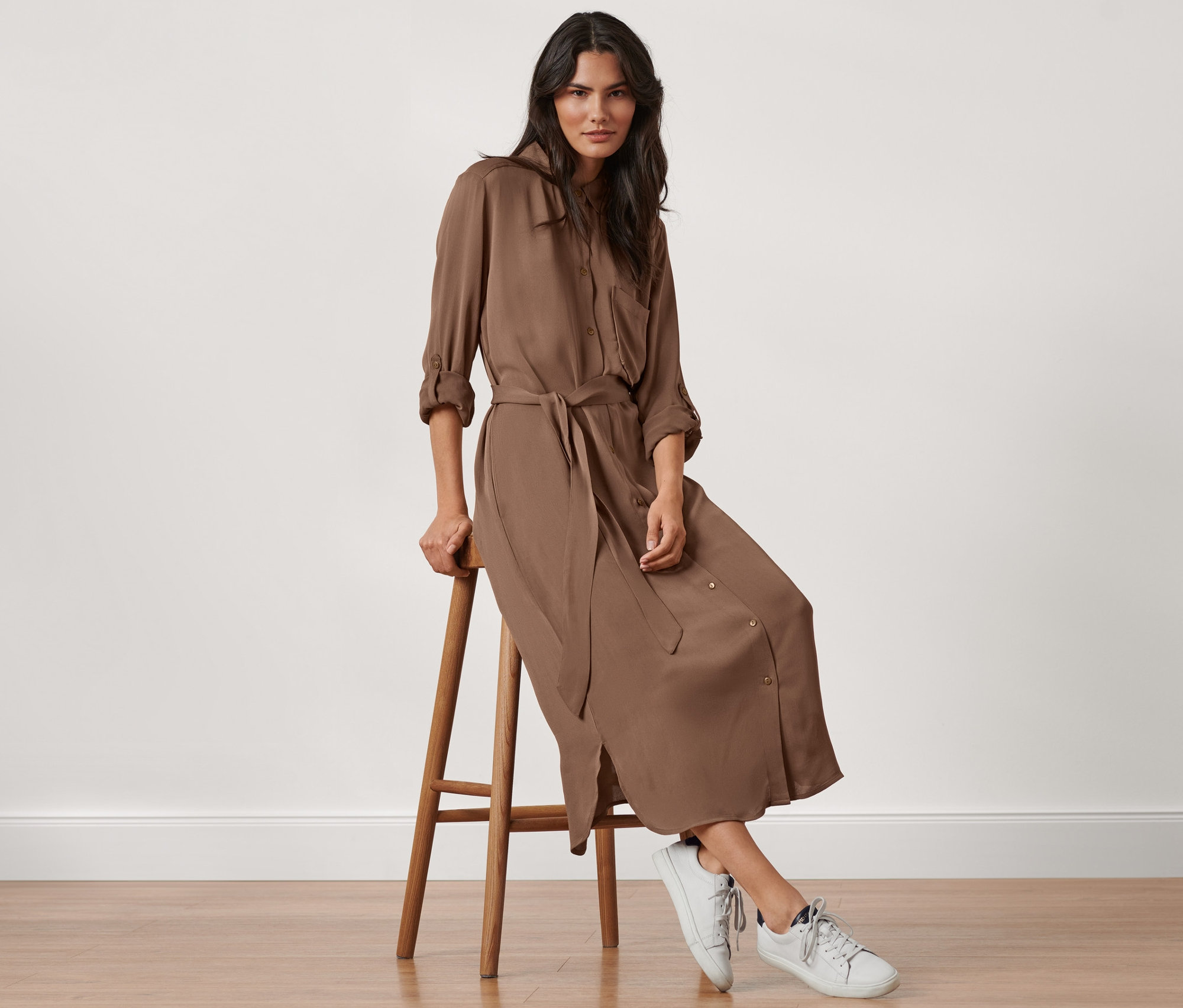 Frau sitzt auf einem Hocker und trägt ein Hemdblusen-Kleid.