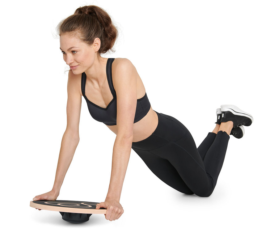Frau macht Liegestütze auf einem Balance-Board.
