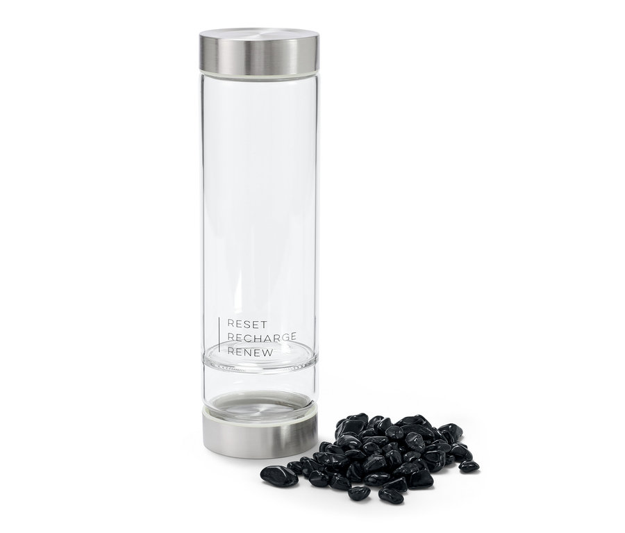 Eine durchsichtige Wasserflasche mit der Aufschrift RESET RECHARGE RENEW und einem Haufen Obsidian daneben.
