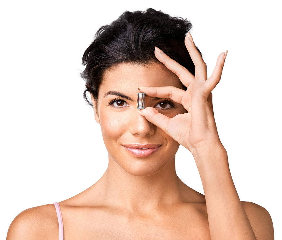 Frau hält Mini-Gesichtsepilierer vor ihrem Auge.