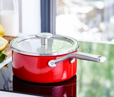 Rote KitchenAid Steel Core Emaille Stielkasserolle mit Deckel auf einem Induktionskochfeld.