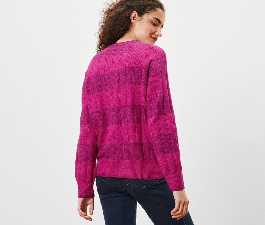 Frau trägt einen Strickpullover mit Ajour-Muster und Jeans.