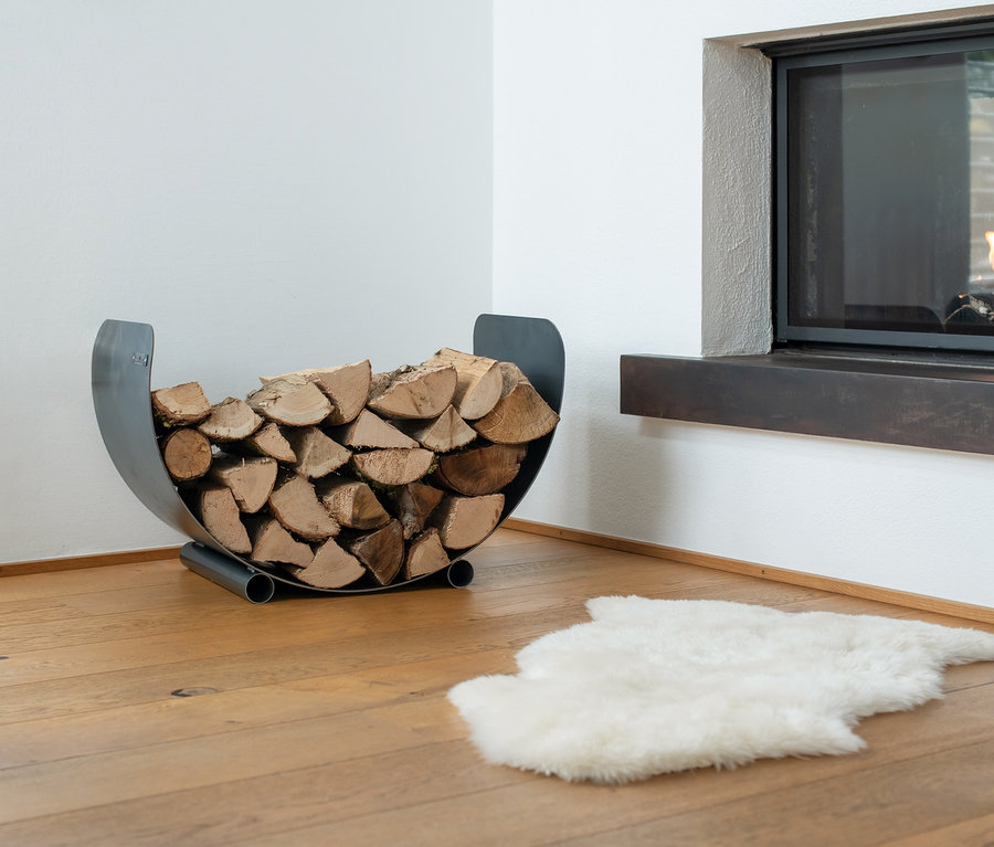 Brennholz lagert in einem Cook King Kaminholzregal neben einem Kamin.