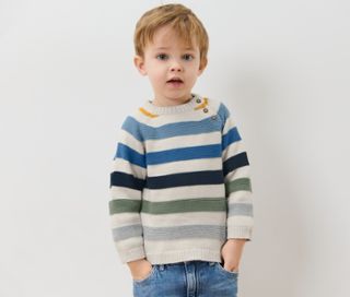 Ein Junge posiert in einem gestreiften Kinder-Strickpullover.