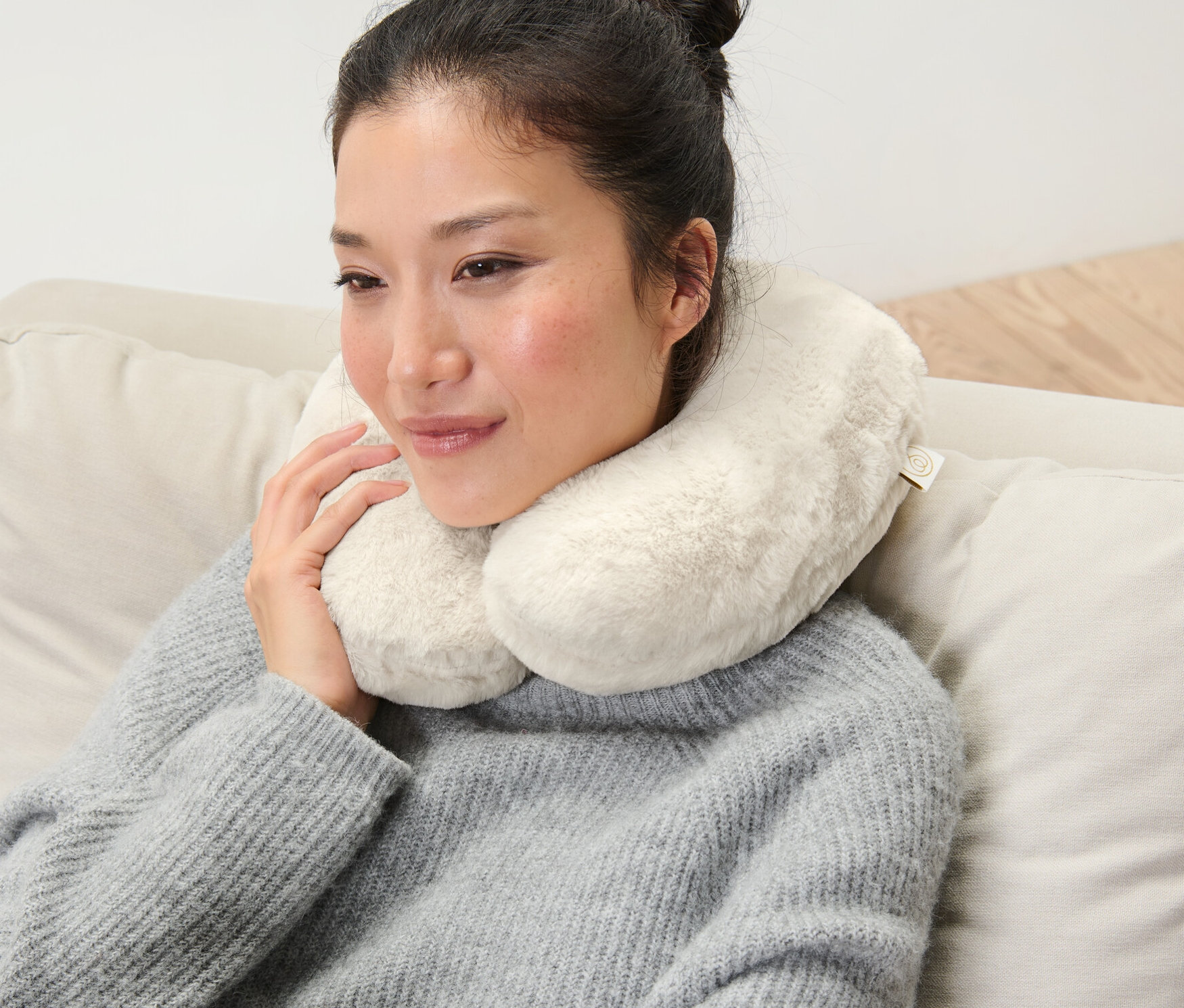 Frau sitzt auf Couch mit einem Memory-Foam-Nackenkissen.