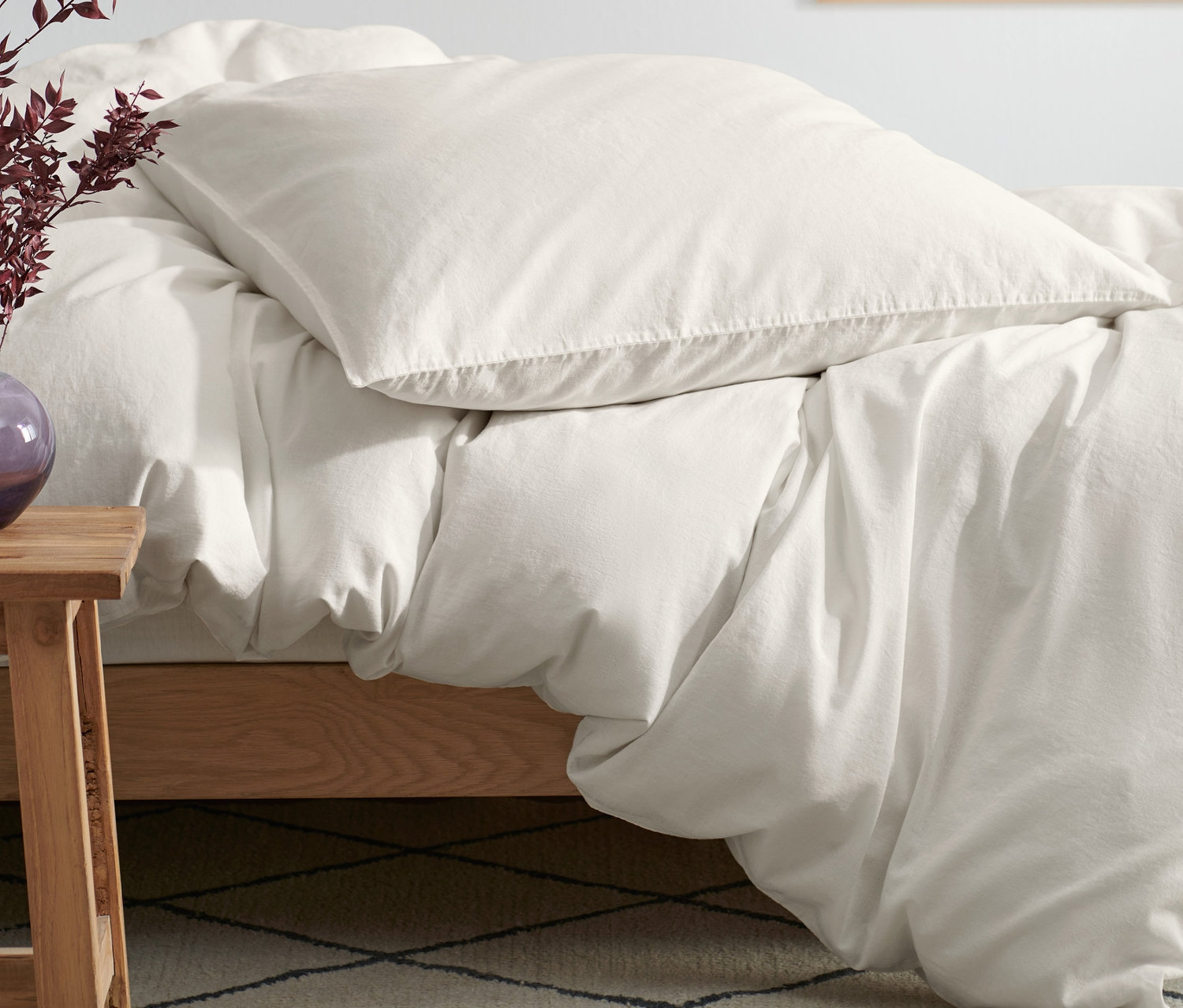 Beige Baumwoll-Leinen-Bettwäsche auf einem Holzbett.