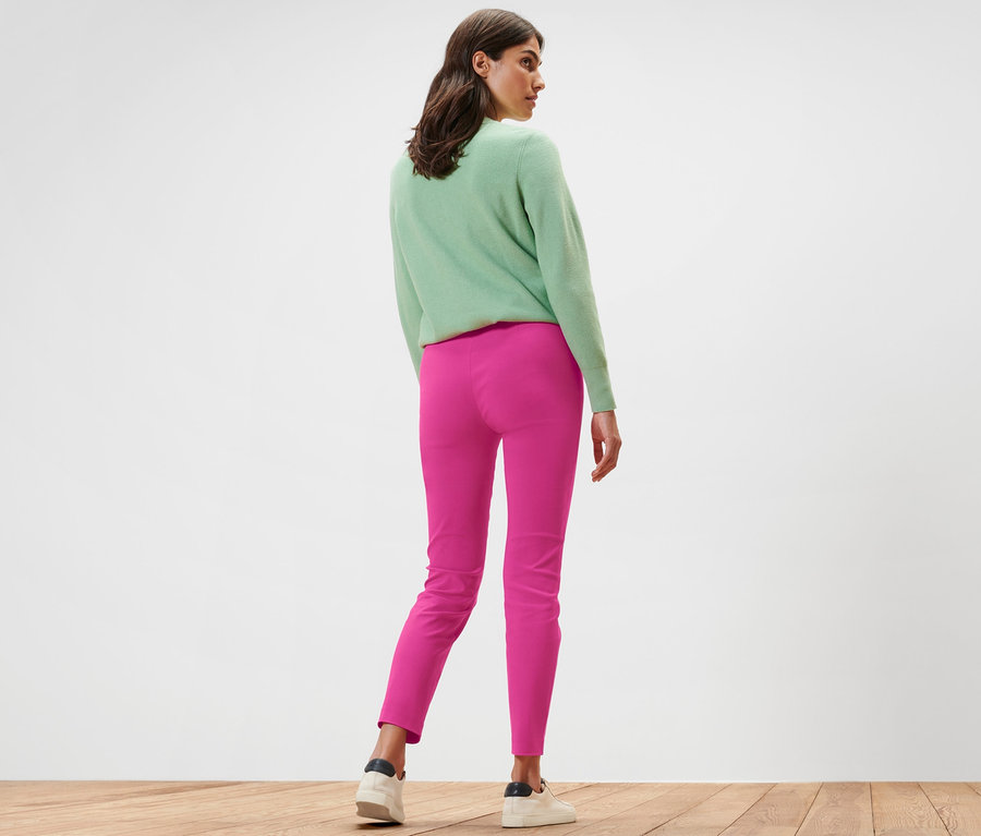 Frau steht mit dem Rücken zur Kamera und trägt eine pinke Stretchhose.