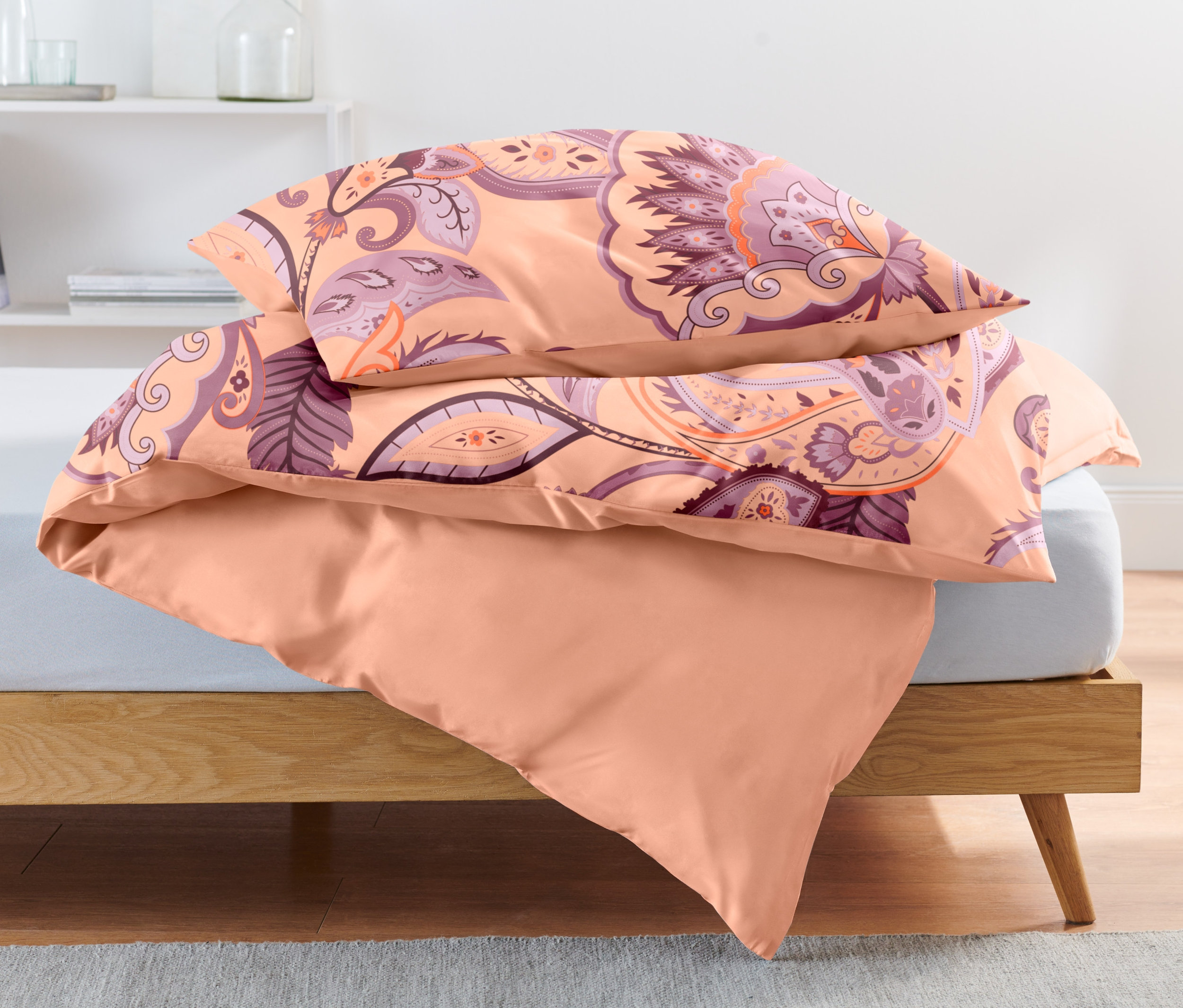 Drei apricotfarbene Renforcé-Bettwäsche-Sets (Normalgröße und Übergröße) liegen auf einem Bett.