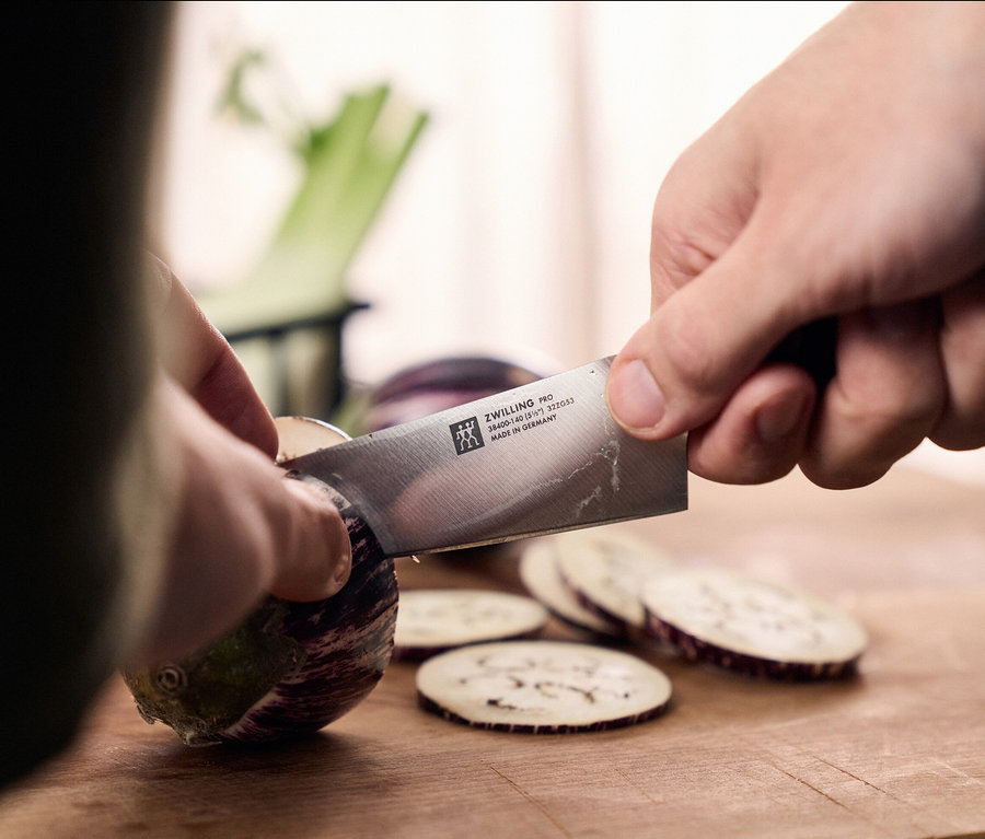 Eine Person schneidet eine Aubergine mit einem Messer aus dem ZWILLING PRO Messerblock.