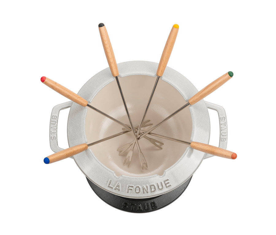 Detailansicht eines weißen STAUB Fondue-Sets mit Holzgriffen und farbigen Enden an den Fonduegabeln.