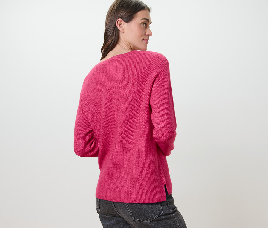 Frau trägt einen himbeerfarbenen Grobstrickpullover.