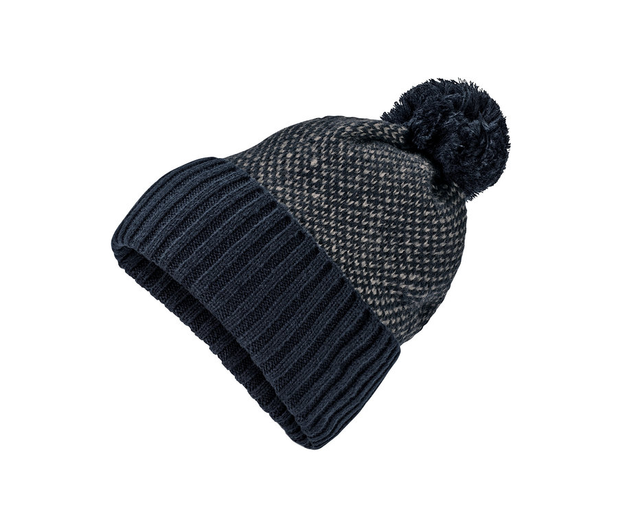 Detailaufnahme einer dunkelblau-beigen Strickmütze mit Bommel auf weißem Hintergrund.