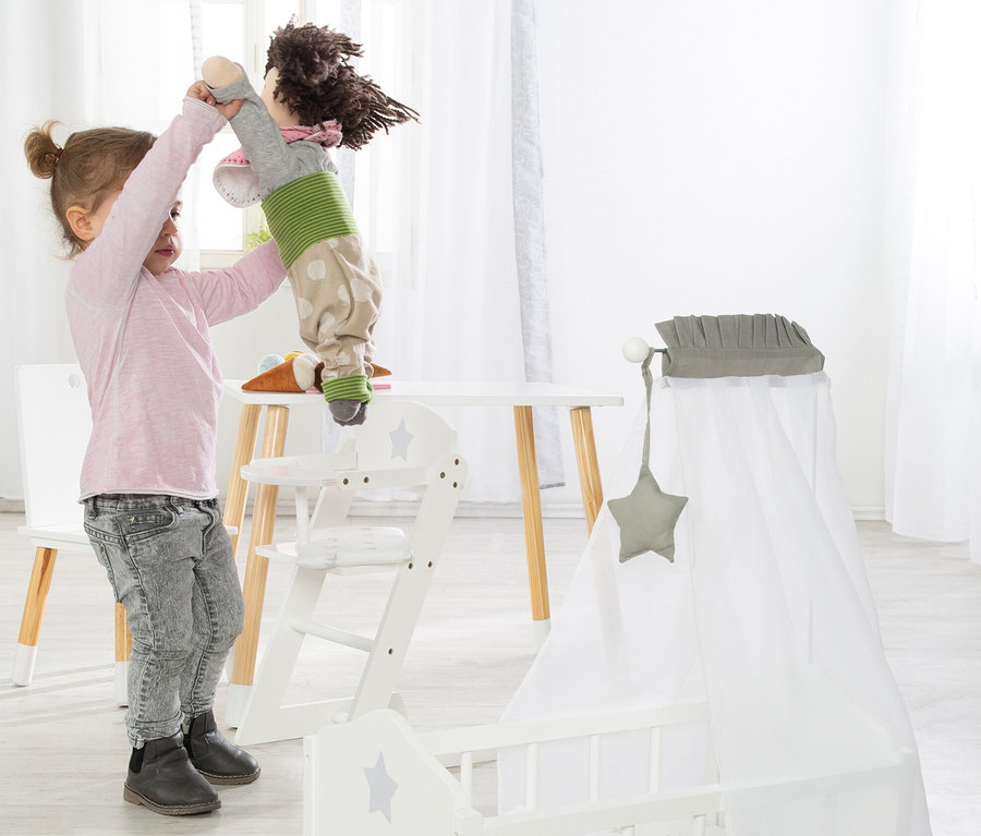 Mädchen hält Puppe über weißem roba Puppenhochstuhl »Stella«.