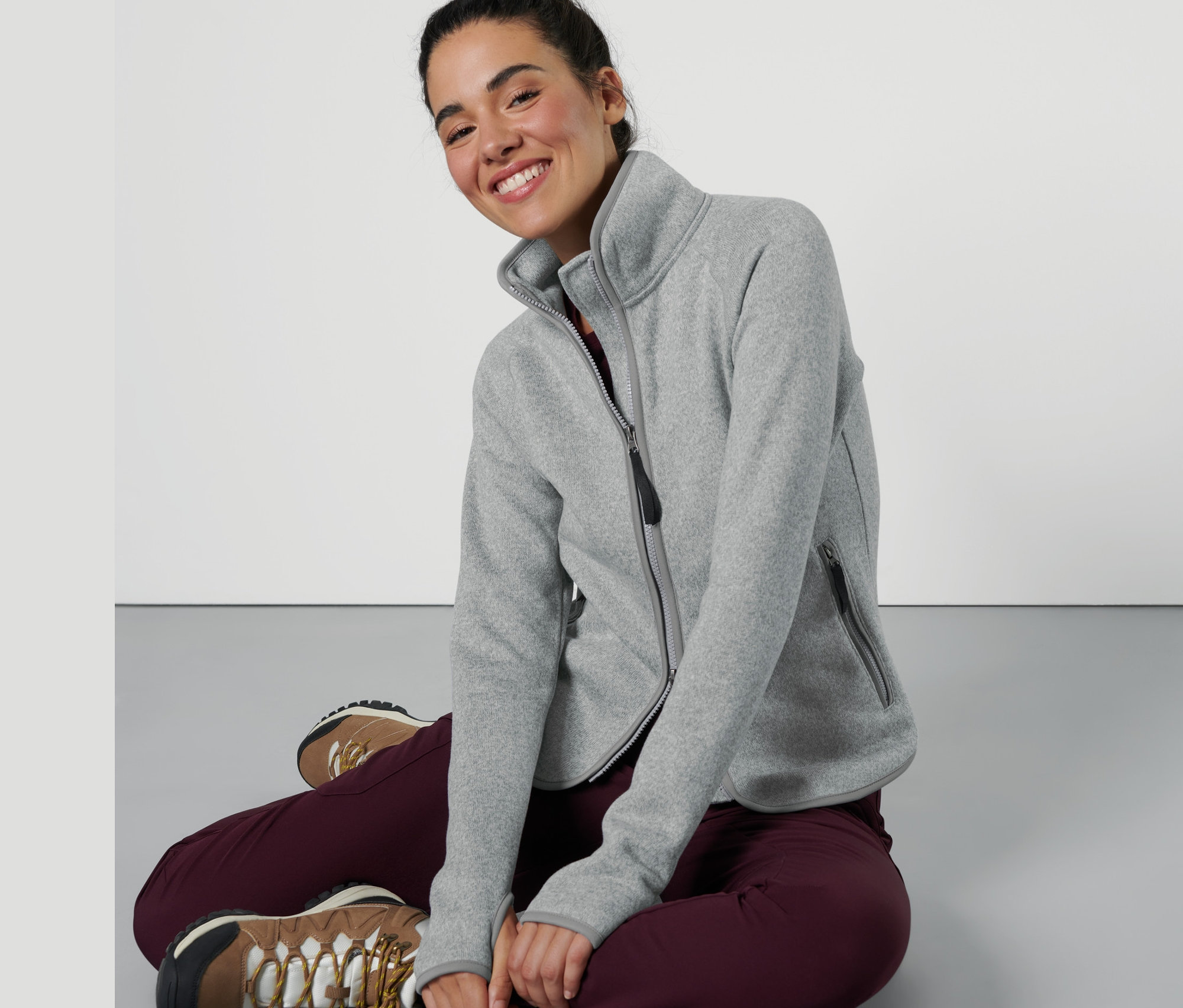 Frau sitzt und trägt eine hellgraue Strickfleece-Jacke.