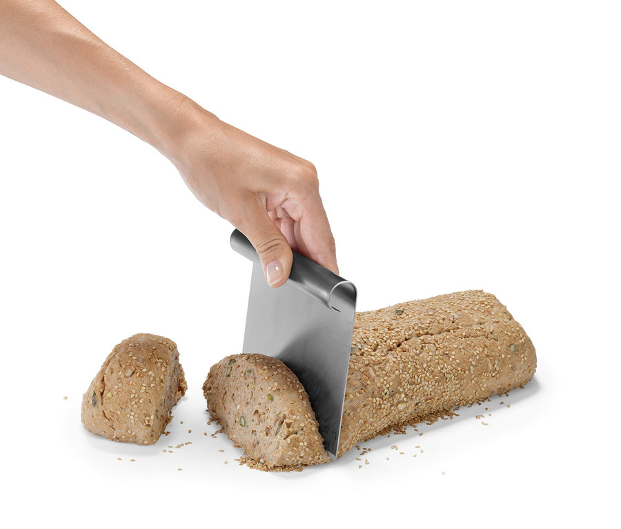 Eine Hand schneidet ein mit Samen bestreutes Brot mit einem Backhelfer-Set.
