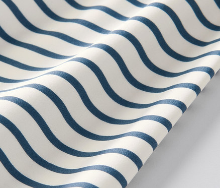 Detailansicht eines Kinder-Shirts mit UV-Schutzfaktor 80 mit blauen Wellen auf weißem Hintergrund.