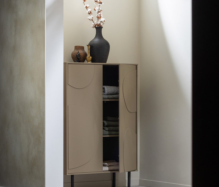 Ein Woood Lagerschrank »Cadiz« aus Kiefernholz steht in einer Ecke des Zimmers. Auf dem Schrank stehen Vasen und Baumwollzweige.
