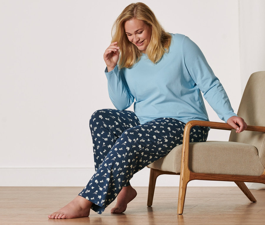 Frau sitzt in einem Sessel und trägt einen Pyjama.