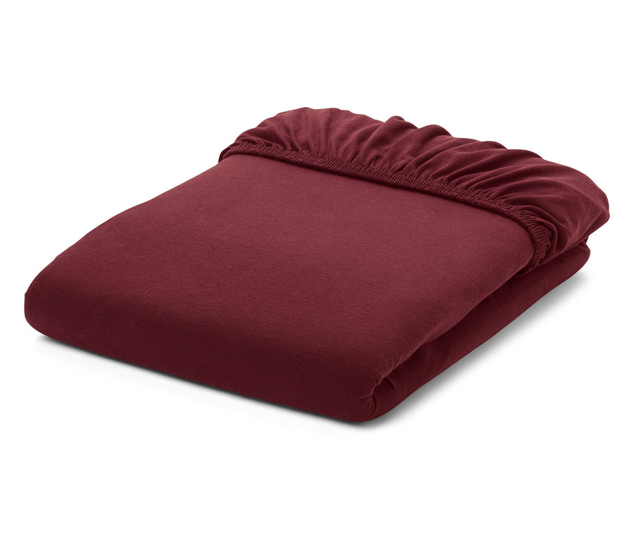 Ein gefaltetes, burgunderrotes Spannbetttuch auf weißem Hintergrund.