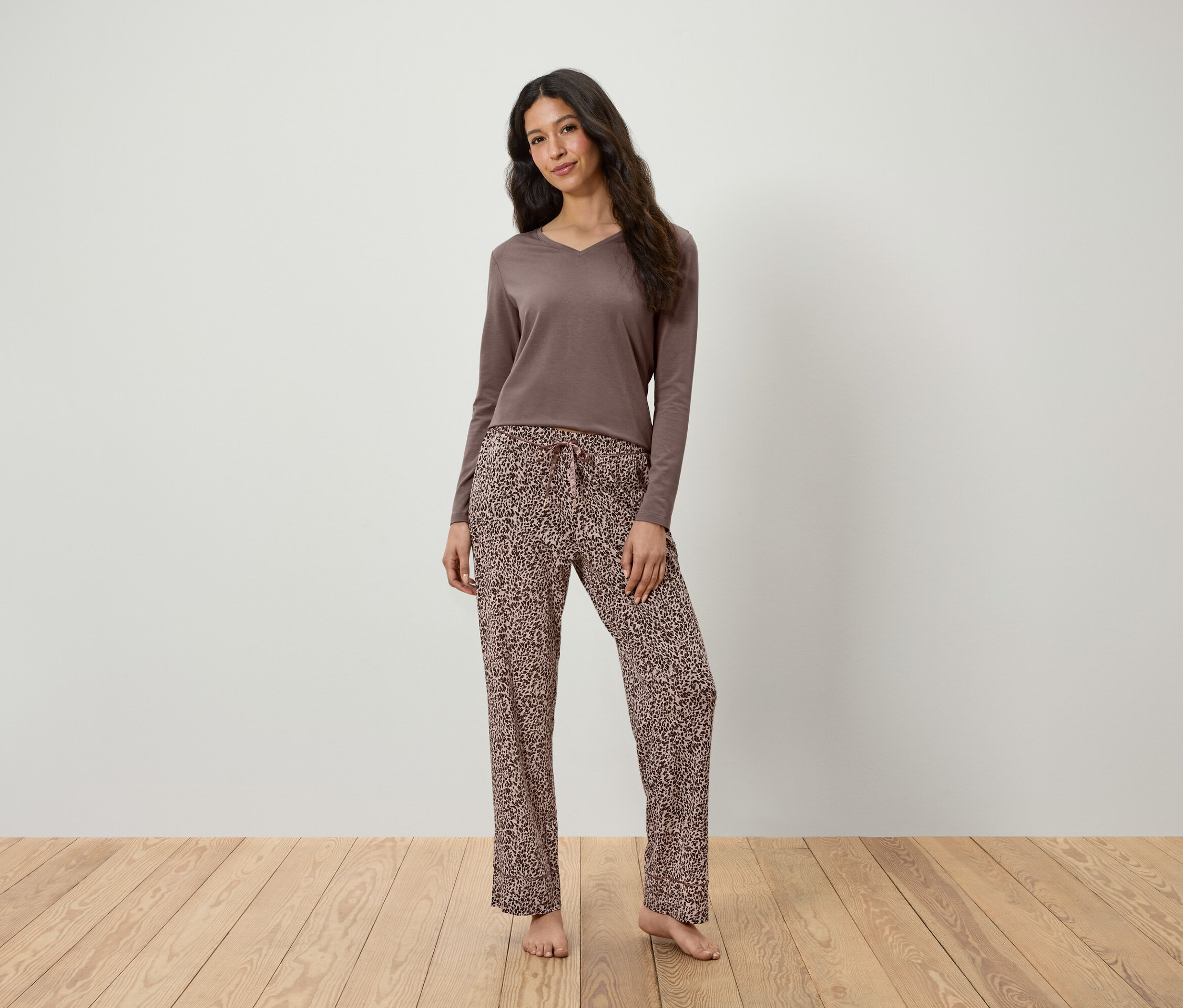 Frau steht und trägt ein braunes Langarmshirt und eine Leopard Hose.