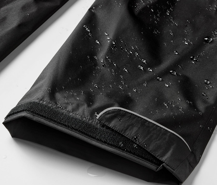 Detailaufnahme einer schwarzen Regenhose mit Wassertropfen.