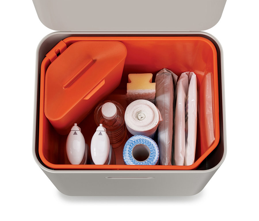 Ein offener grauer Behälter mit orangefarbenem Inneren, gefüllt mit einem Erste-Hilfe-Kasten.