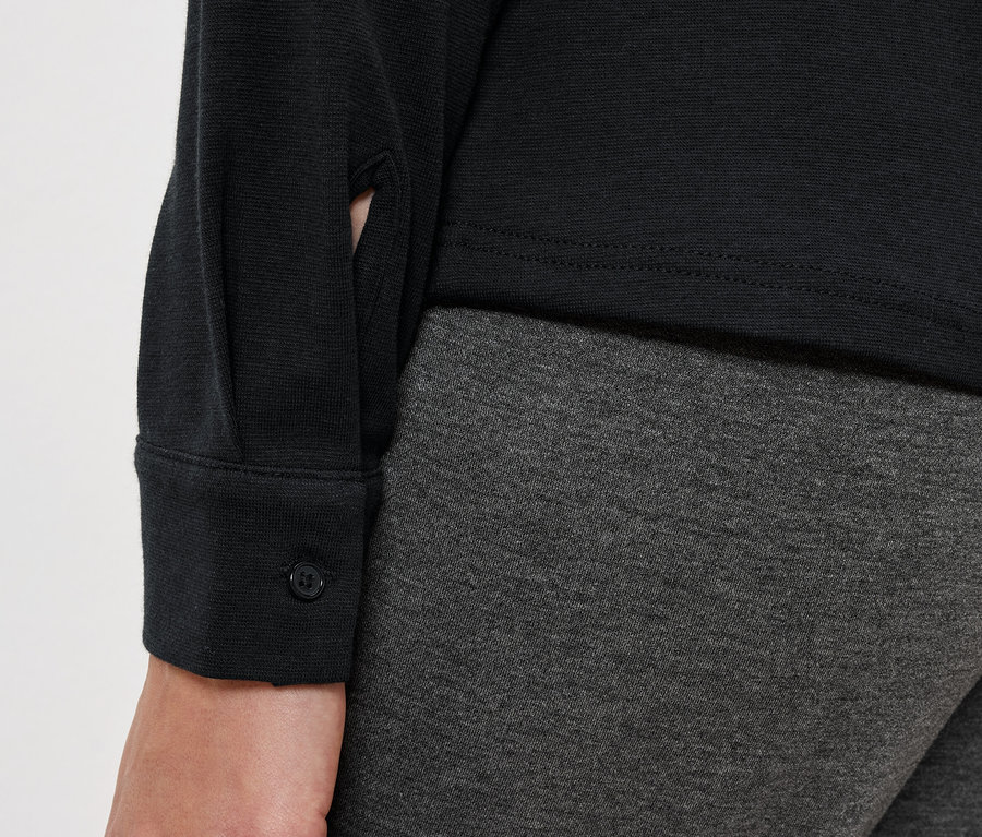 Detailaufnahme eines Damenoutfits mit schwarzer Bluse und grauen Leggings.